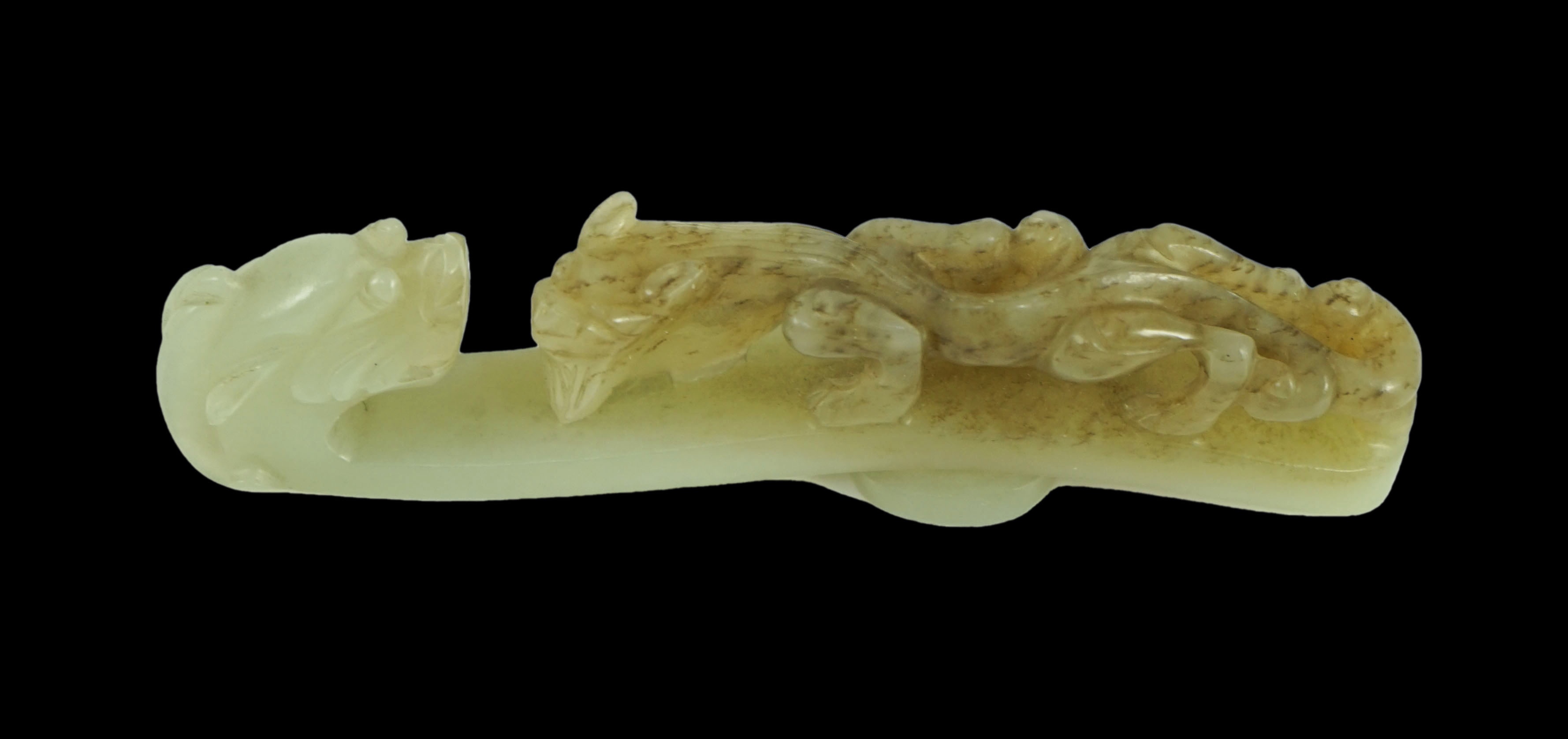 A Chinese pale celadon and brown jade ‘dragon’ belt hook, 18th/19th century 10.7 cm long